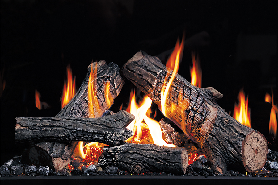 Fireplace with burning logs and bright orange flames against a dark background, creating a cozy indoor scene.
